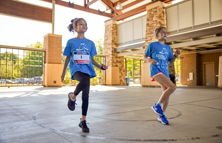 Girls on the Run participants run outside during program practice smiling Girls on the Run participants run outside during program practice smiling