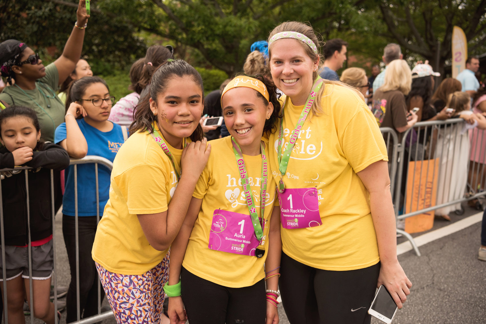 Three girls in yellow shirts smiling.